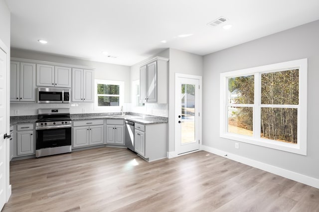 kitchen with stainless steel appliances, sink, light hardwood / wood-style flooring, and gray cabinetry