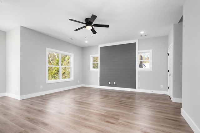 empty room featuring ceiling fan, a wealth of natural light, and light hardwood / wood-style floors