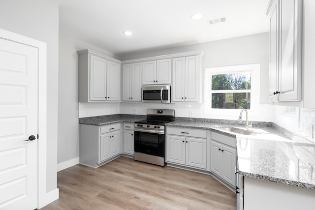 kitchen featuring light wood-type flooring, stainless steel appliances, sink, and white cabinets