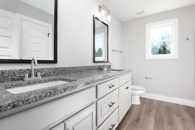 bathroom with hardwood / wood-style flooring, plenty of natural light, toilet, and vanity