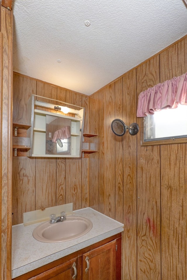 bathroom featuring vanity, wooden walls, and a textured ceiling