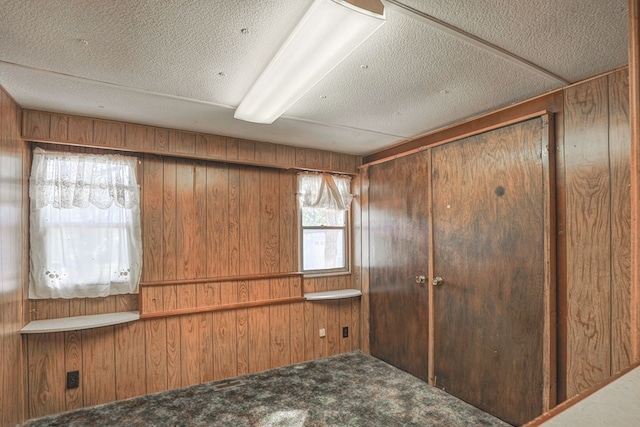 unfurnished bedroom featuring carpet flooring, wooden walls, and a closet