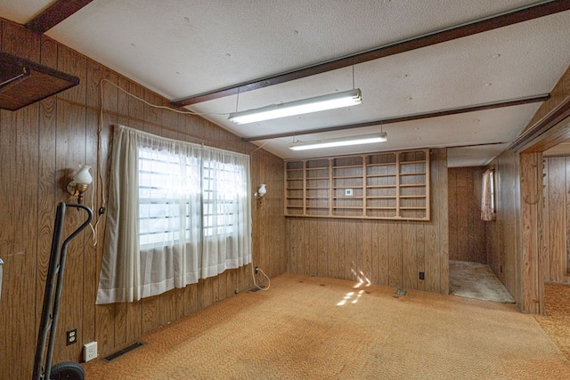 spare room featuring vaulted ceiling with beams, carpet, and wood walls