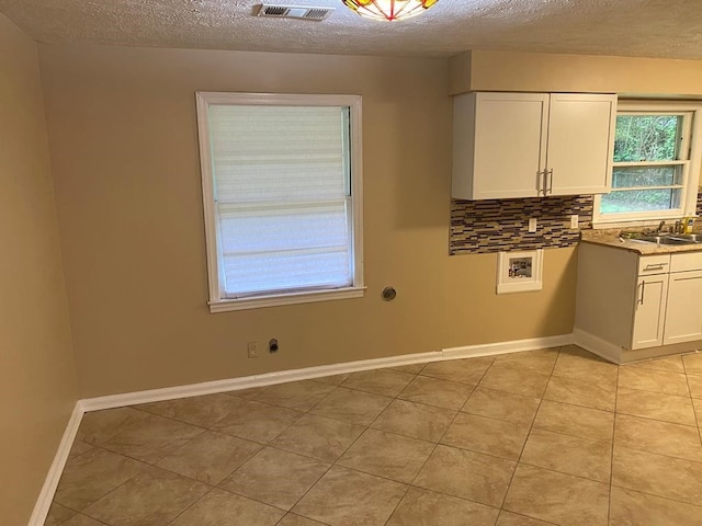 kitchen featuring white cabinets, a textured ceiling, sink, and backsplash