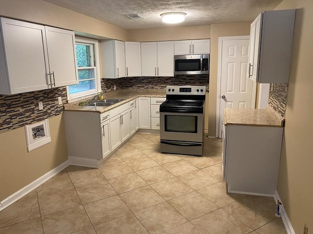 kitchen featuring sink, a textured ceiling, appliances with stainless steel finishes, tasteful backsplash, and white cabinetry