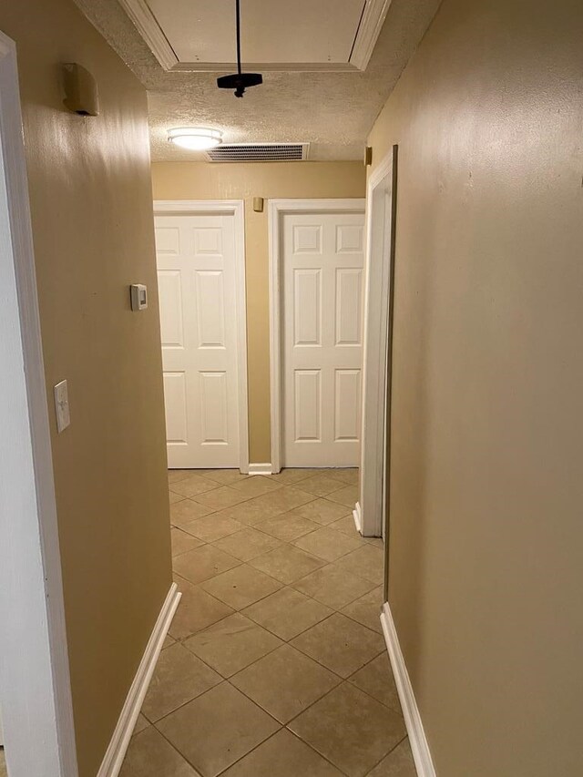 hall featuring light tile patterned floors and a textured ceiling