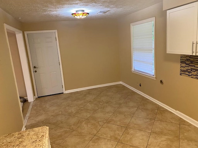 unfurnished dining area with a textured ceiling