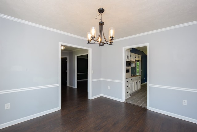 empty room with a chandelier, dark wood-style flooring, baseboards, and crown molding