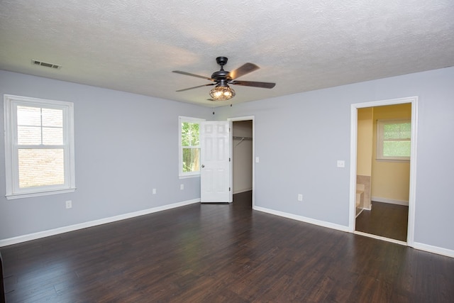 unfurnished bedroom featuring dark wood-type flooring, multiple windows, and a textured ceiling