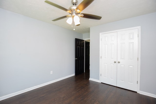 unfurnished bedroom featuring dark wood-style floors, baseboards, a closet, and a ceiling fan