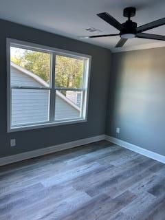 spare room featuring ceiling fan, a healthy amount of sunlight, and wood-type flooring