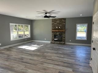 unfurnished living room with ceiling fan, a fireplace, and dark hardwood / wood-style floors