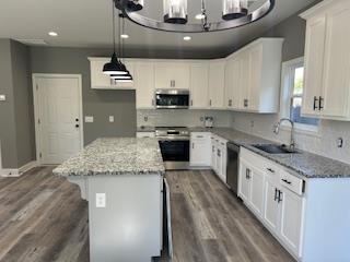 kitchen featuring a kitchen island, light stone countertops, sink, and stainless steel appliances