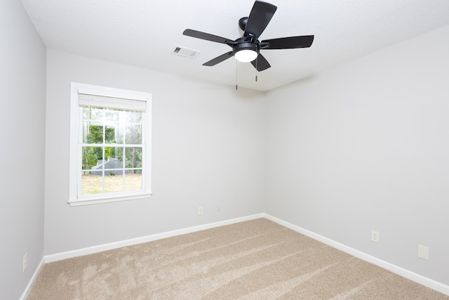 carpeted spare room featuring baseboards, ceiling fan, a textured ceiling, and visible vents