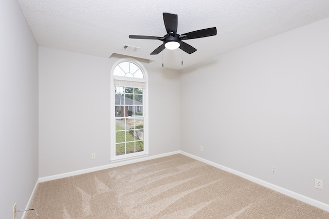 carpeted empty room with a ceiling fan, baseboards, visible vents, and a textured ceiling