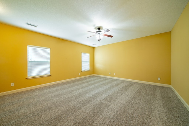 spare room with visible vents, a ceiling fan, carpet, and baseboards