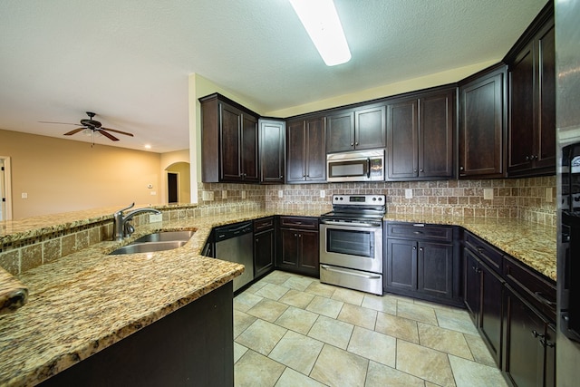 kitchen featuring a sink, light stone counters, backsplash, and appliances with stainless steel finishes