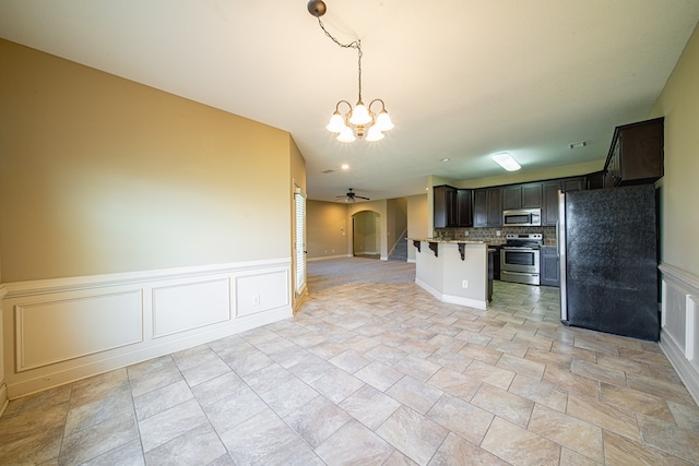 kitchen with backsplash, open floor plan, a breakfast bar area, appliances with stainless steel finishes, and arched walkways