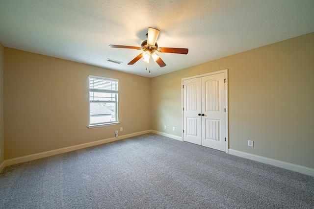 unfurnished room featuring a ceiling fan, carpet, visible vents, baseboards, and a textured ceiling