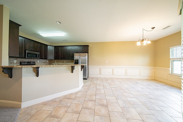 kitchen with a kitchen breakfast bar, light stone countertops, visible vents, and stainless steel appliances