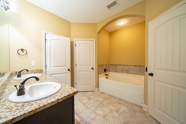 bathroom featuring a sink, visible vents, a bath, and double vanity