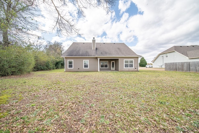 back of house with a lawn, a chimney, and fence