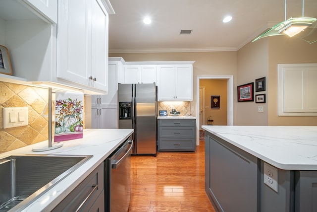 kitchen featuring white cabinetry, crown molding, decorative backsplash, and appliances with stainless steel finishes