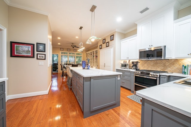 kitchen featuring gray cabinetry, stainless steel appliances, hanging light fixtures, and white cabinets