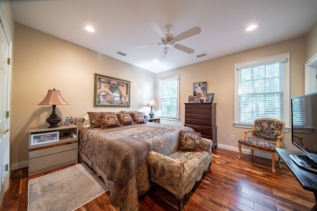 bedroom featuring multiple windows, dark hardwood / wood-style floors, and ceiling fan