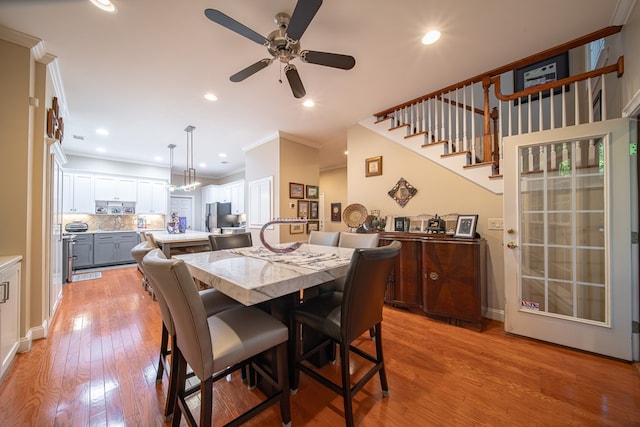 dining space featuring ornamental molding, ceiling fan, and light hardwood / wood-style flooring