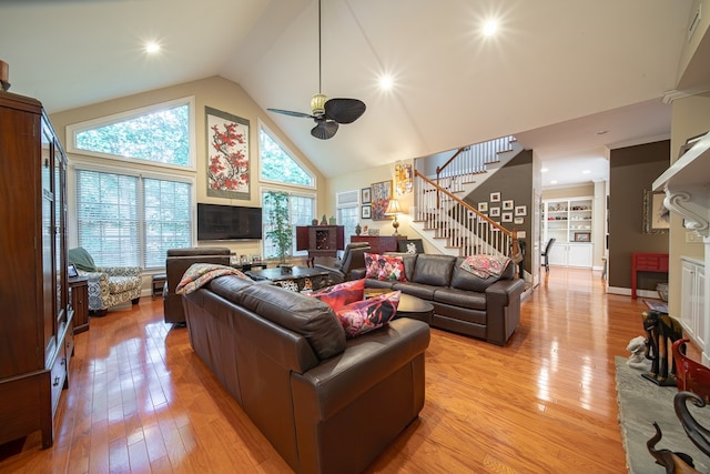 living room with ceiling fan, light hardwood / wood-style floors, and high vaulted ceiling