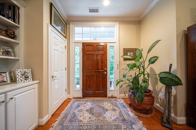 foyer entrance featuring ornamental molding, a wealth of natural light, and light wood-type flooring