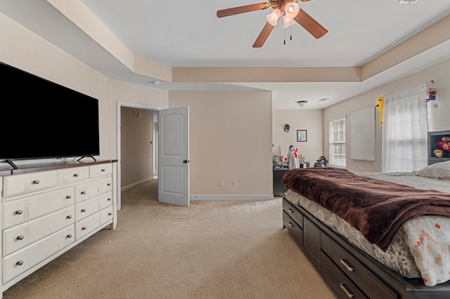 carpeted bedroom featuring a raised ceiling and ceiling fan