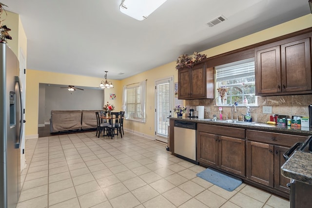 kitchen with light tile patterned floors, decorative backsplash, dark brown cabinets, and stainless steel appliances