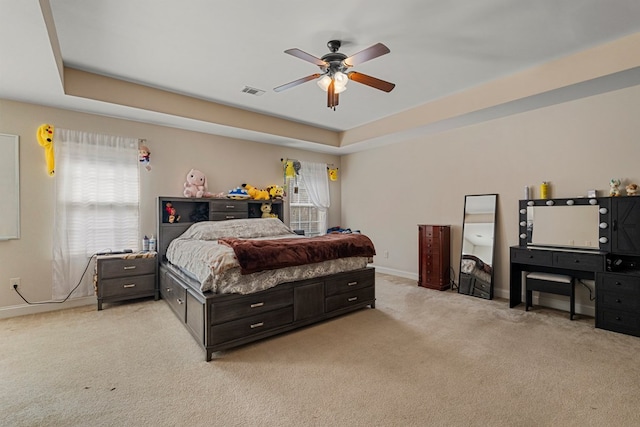 carpeted bedroom featuring ceiling fan and a tray ceiling