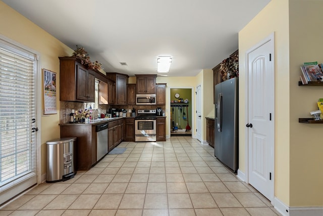 kitchen featuring backsplash, dark brown cabinets, stainless steel appliances, and light tile patterned flooring