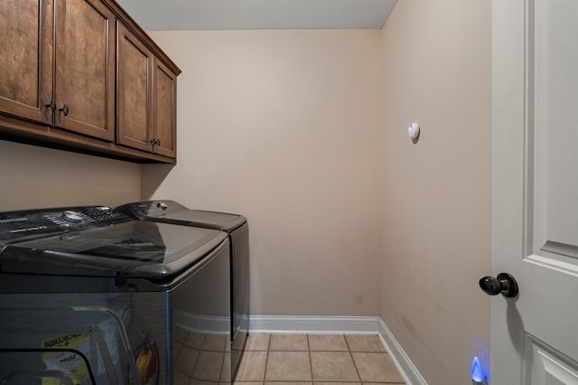 laundry area with cabinets, light tile patterned floors, and washer and clothes dryer