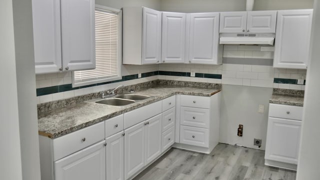 2830 N Lumpkin Rd, Columbus, GA 31903 - kitchen with under cabinet range hood, a sink, backsplash, white cabinets, and light wood-type flooring