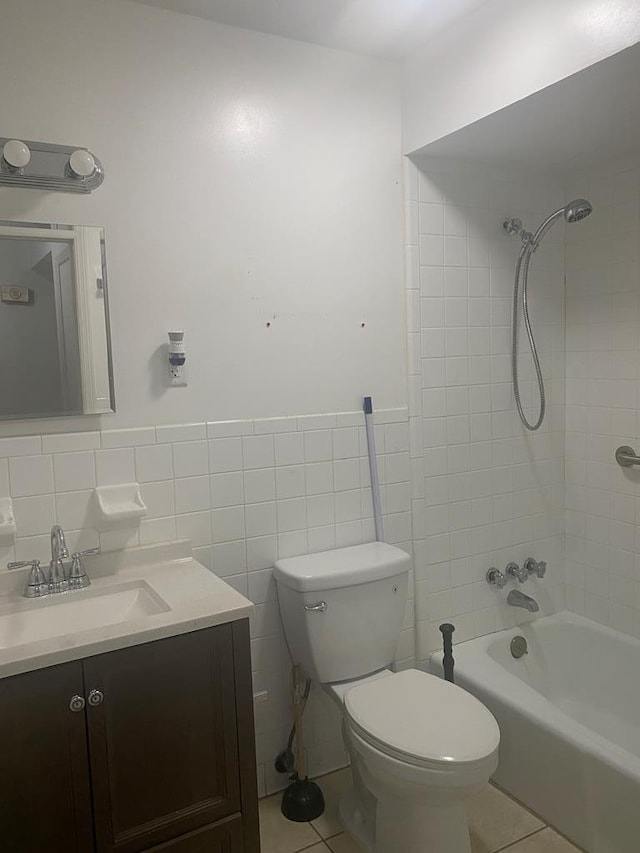 bathroom featuring shower / tub combination, toilet, tile patterned flooring, vanity, and tile walls