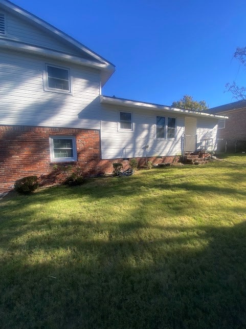 back of house featuring a yard and brick siding