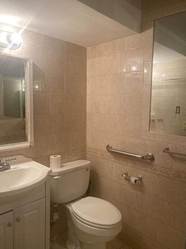 bathroom featuring toilet, vanity, and tile walls