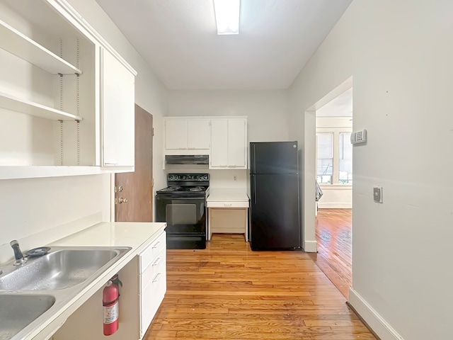 kitchen with black appliances, white cabinets, light wood-type flooring, and sink