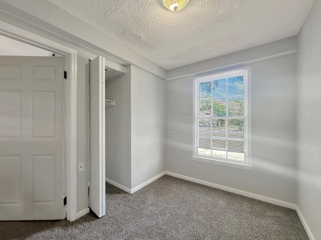 carpeted empty room featuring a textured ceiling