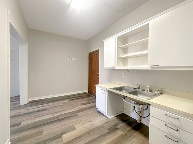 kitchen with white cabinets, light wood-type flooring, and sink