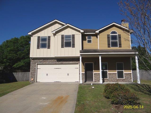 1111 Richland Dr, Columbus, GA 31907 - view of front of house featuring an attached garage, stone siding, concrete driveway, and fence
