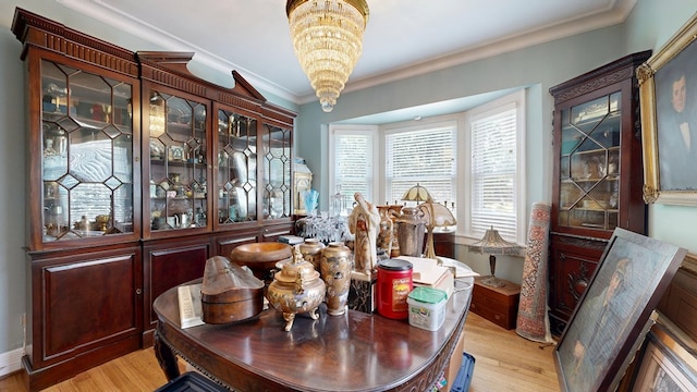 dining room with ornamental molding, light wood-style flooring, and a chandelier
