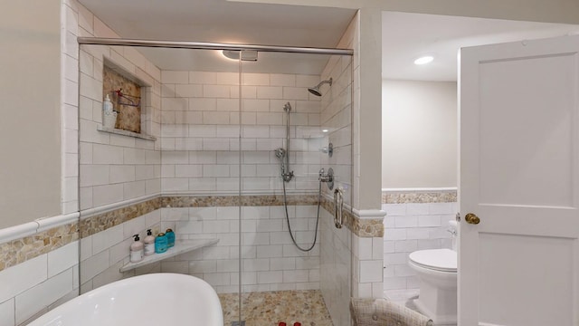 bathroom featuring toilet, tile walls, a shower stall, and a wainscoted wall
