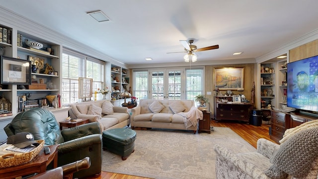living room with crown molding, ceiling fan, a wealth of natural light, and wood finished floors