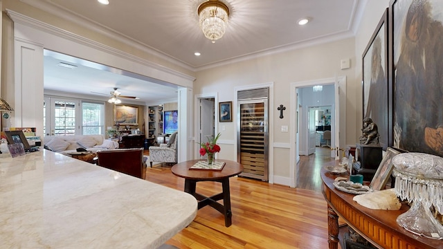 interior space with beverage cooler, ornamental molding, and light wood-style floors