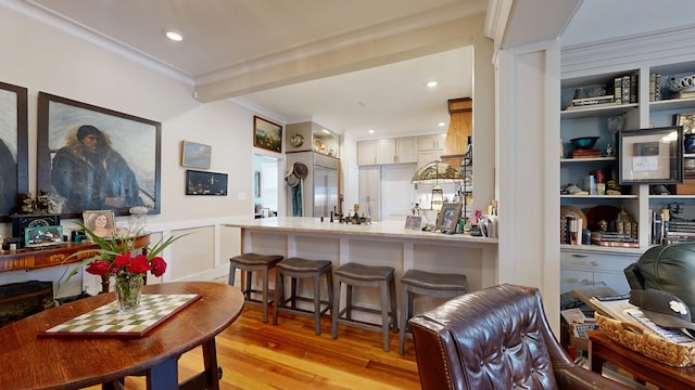 interior space with light wood-type flooring, light countertops, a wainscoted wall, a peninsula, and open floor plan